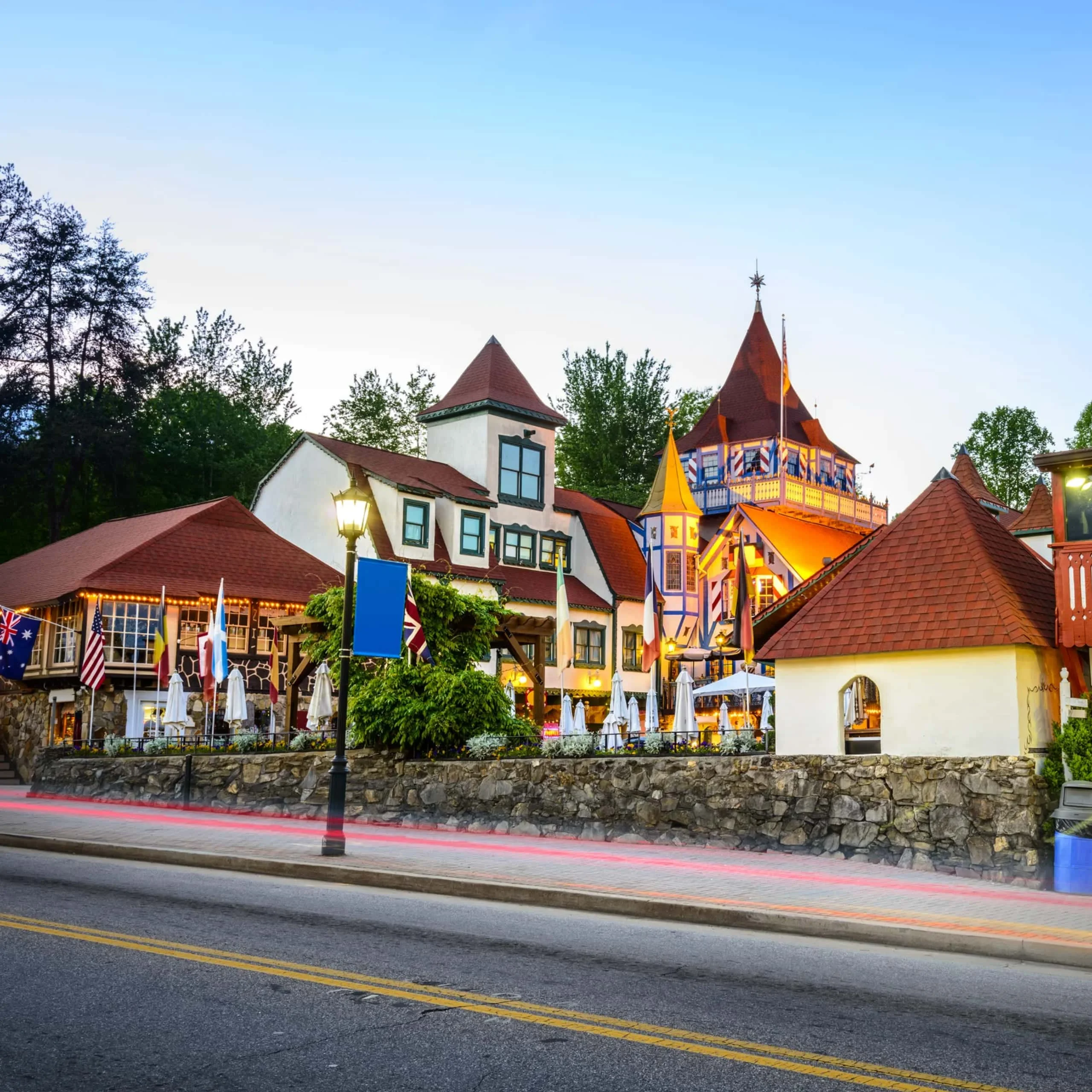 Bavarian-style buildings with pointed roofs and flags at the Alpine Village in Helen, Georgia. - Lederhosen For Sale