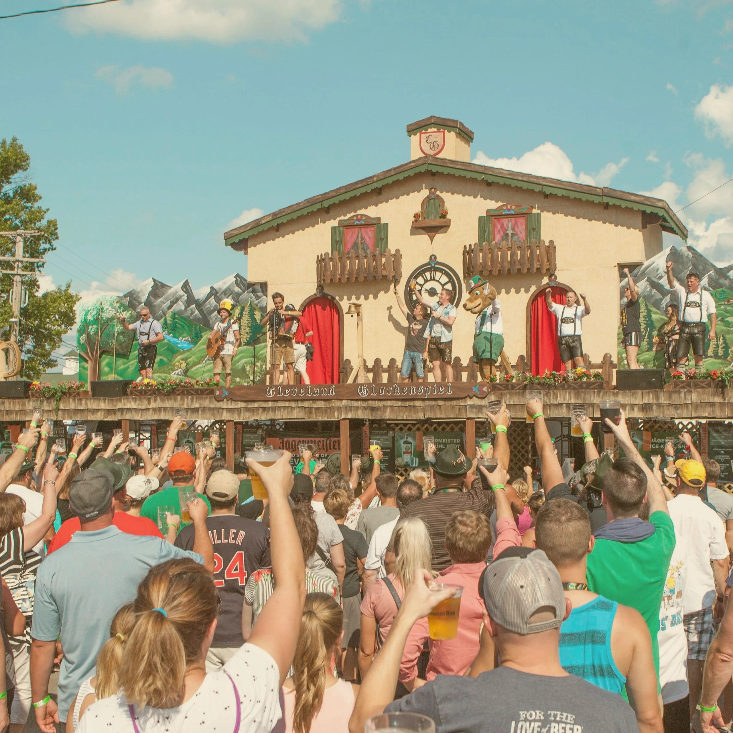 A large crowd of people raising beer mugs toward a stage at the Cleveland Oktoberfest in Missouri. - Lederhosen For Sale