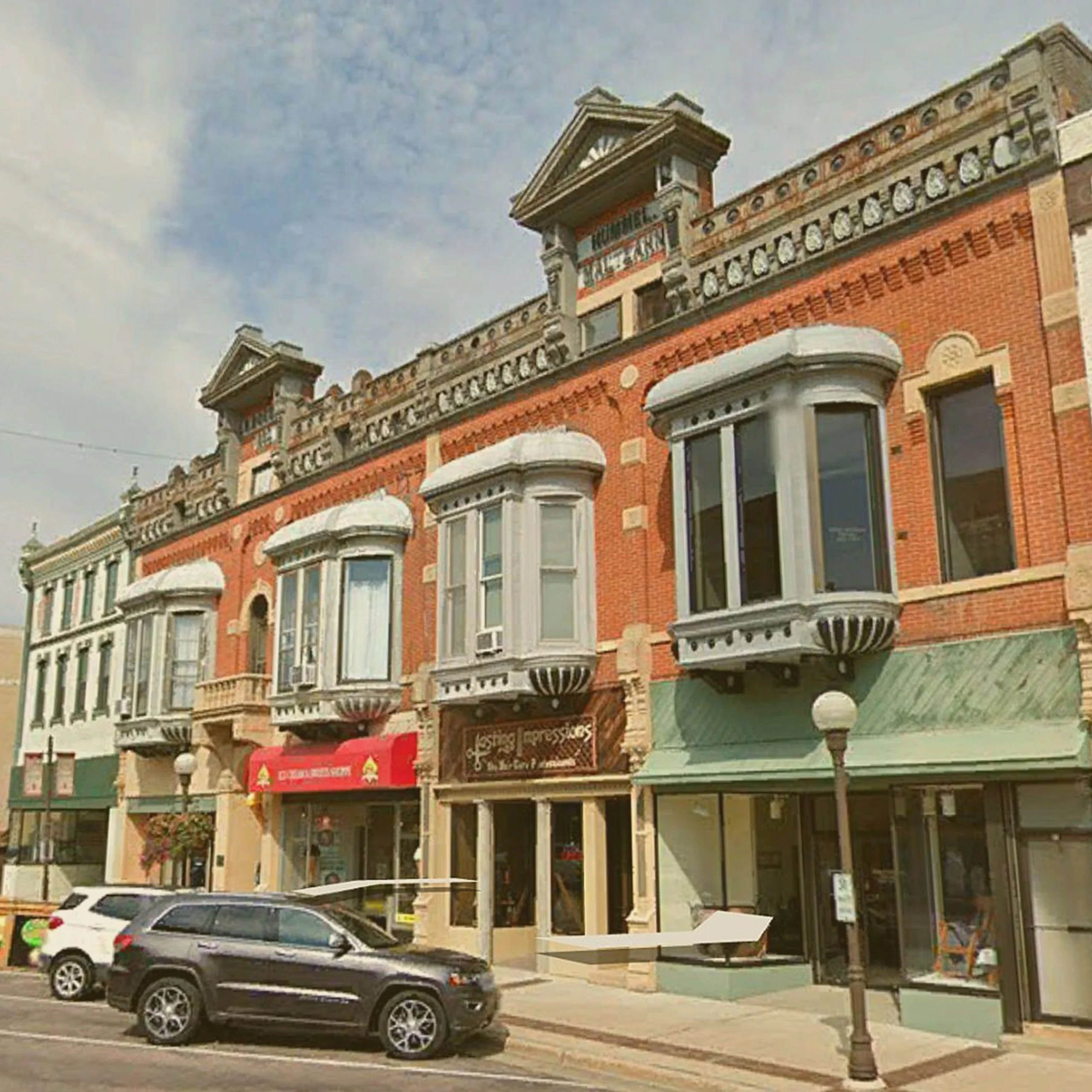 A row of historic brick storefronts on a city street, including the Boesch, Hummel, and Maltzahn Block building in New Ulm. - Lederhosen For Sale