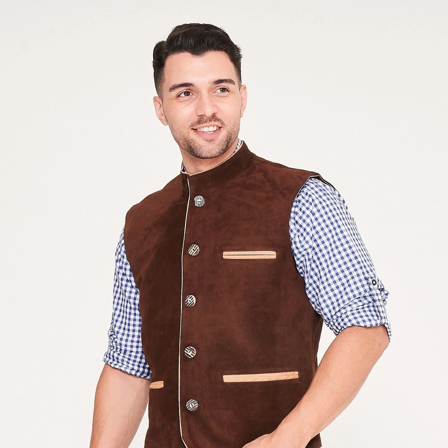 Man wearing a brown Bavarian suede vest with ornate buttons over a blue checkered shirt. - Lederhosen For Sale